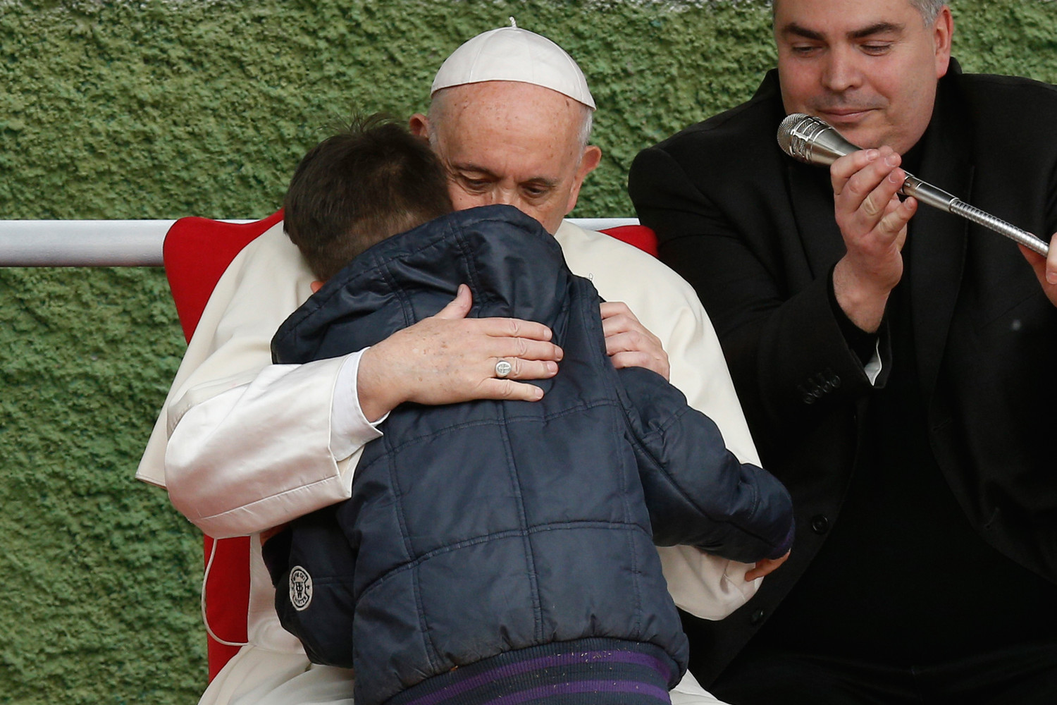 Pope Francis embraces Emanuele, a boy whose father died, as he visits St. Paul of the Cross Parish in Rome April 15.